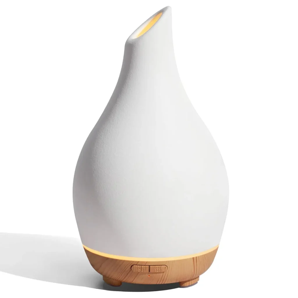 Sleek white aromatherapy diffuser with a wooden base and gentle glowing light, perfect for creating a calming atmosphere at home