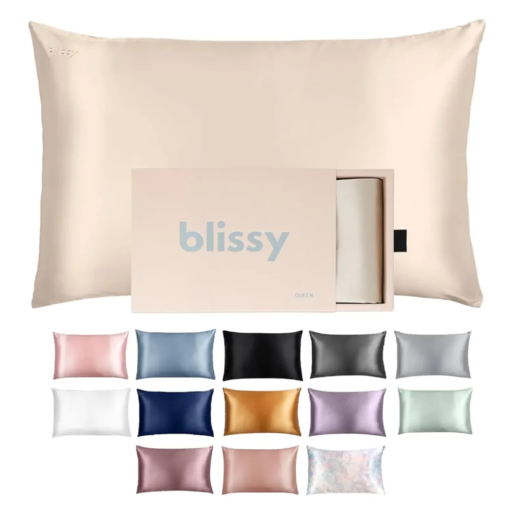Large champagne-colored silk pillowcase with packaging box and smaller pillow samples showing full color palette, designed to keep hair smooth and skin healthy, perfect for luxurious sleep and self-care