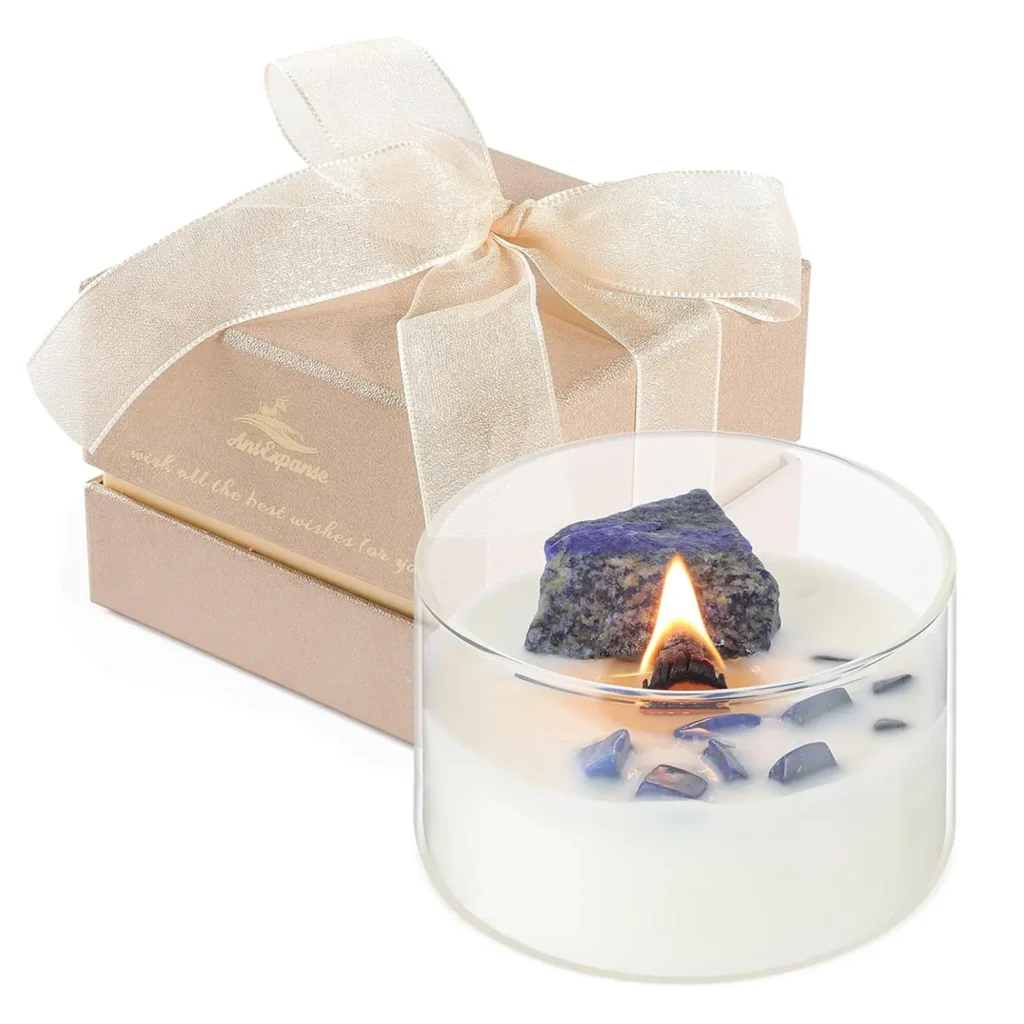 Beautiful crystal-infused candle in a clear glass jar with white wax and thick wooden wick, decorated with purple crystals, with a beige gift box and delicate bow in the background, perfect for gifting or home decor