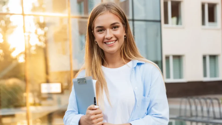 Young professional woman in formal office outfit posing confidently in front of a modern office building, representing success and career focus.