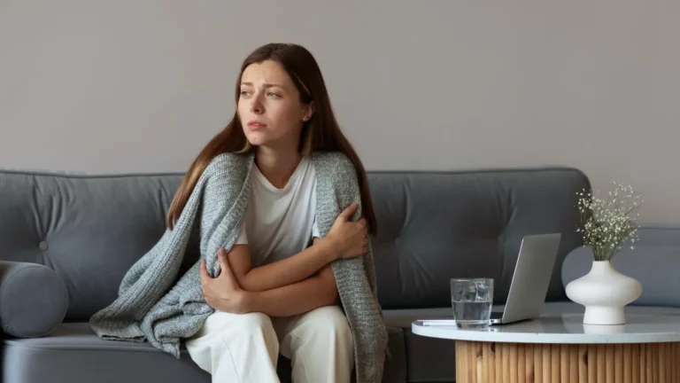Adult brunette woman sitting alone on a couch, looking sad and contemplative, expressing loneliness and deep emotion in a cozy indoor setting