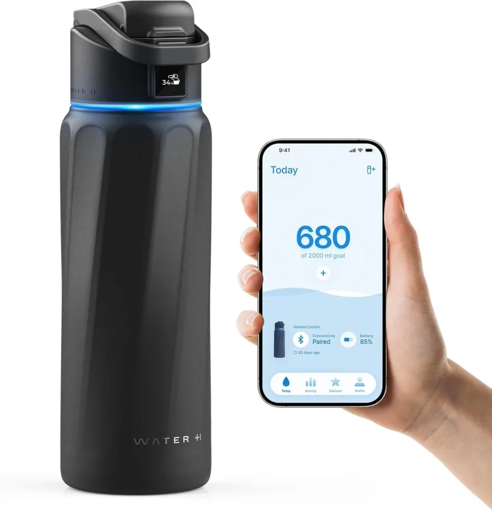 Black smart water bottle on a white background with a hand holding a smartphone showing the hydration tracking app, designed to remind and track daily water intake for healthy hydration habits.
